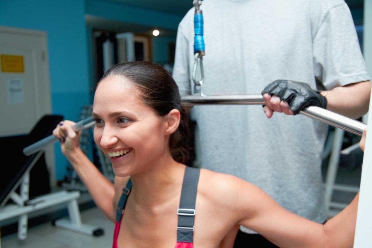 Woman smiling while exercising on lat pulldown machine