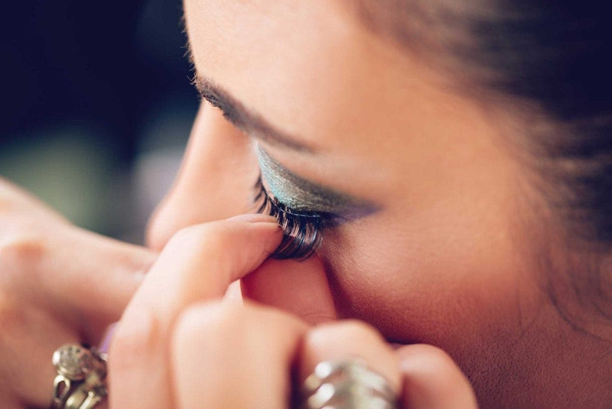 Close-up of woman applying blue eyelash makeup
