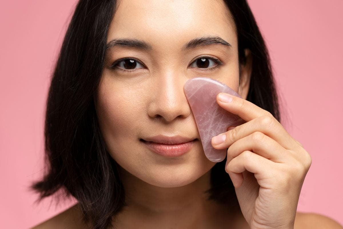 Woman using pink facial gua sha tool