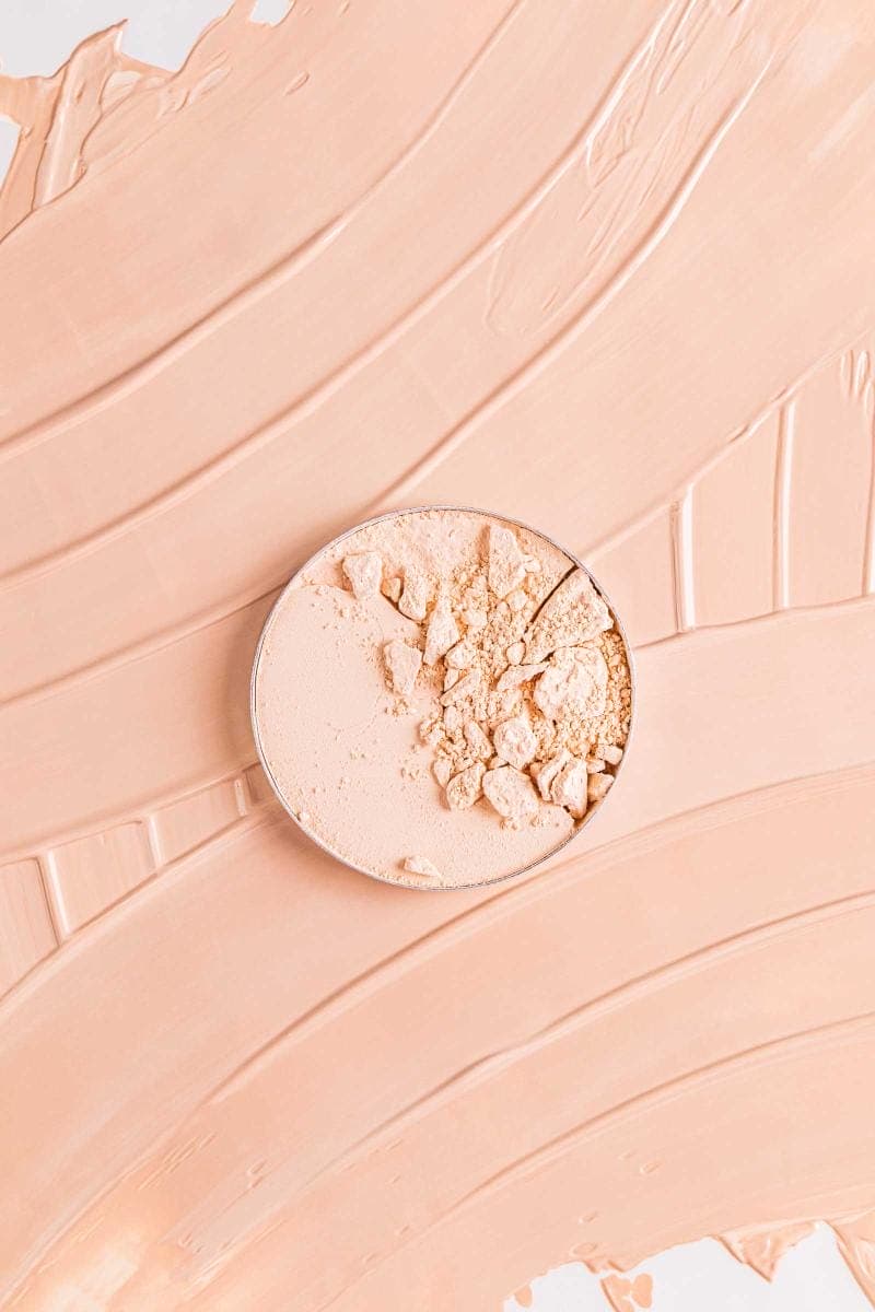 Crumbled powder in circular tin on soft surface